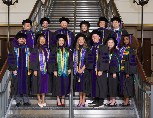 A group of law students in regalia posing on the College of Law staircase.