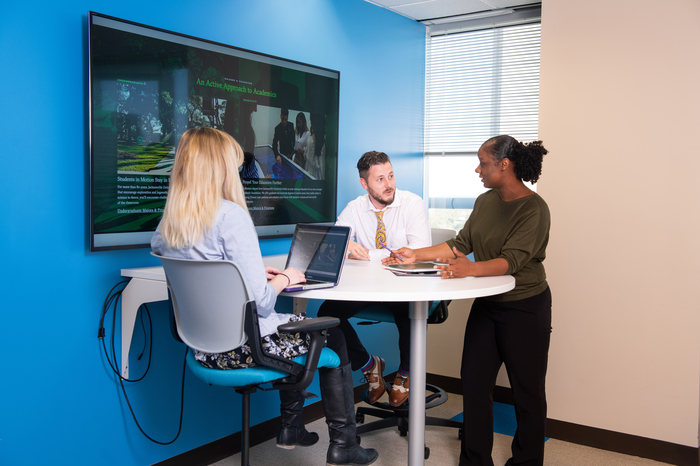 Three business professionals chat during a meeting