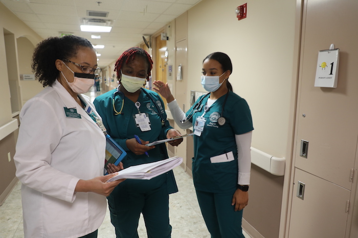 Two nurses in training meet with a supervisor at a hospital before going in to a patients room for a consult
