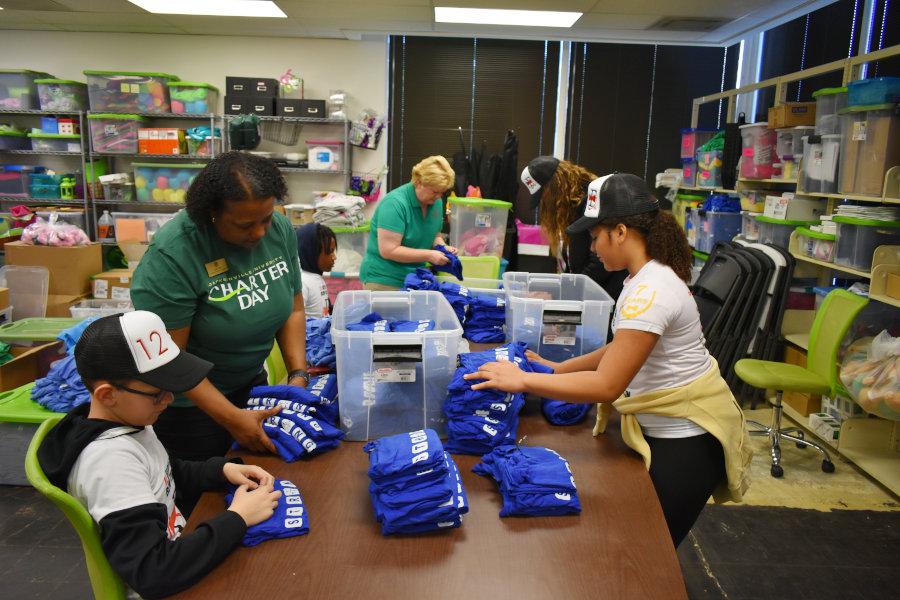 Charter Day Volunteers sorting clothing items at a Community Partner location