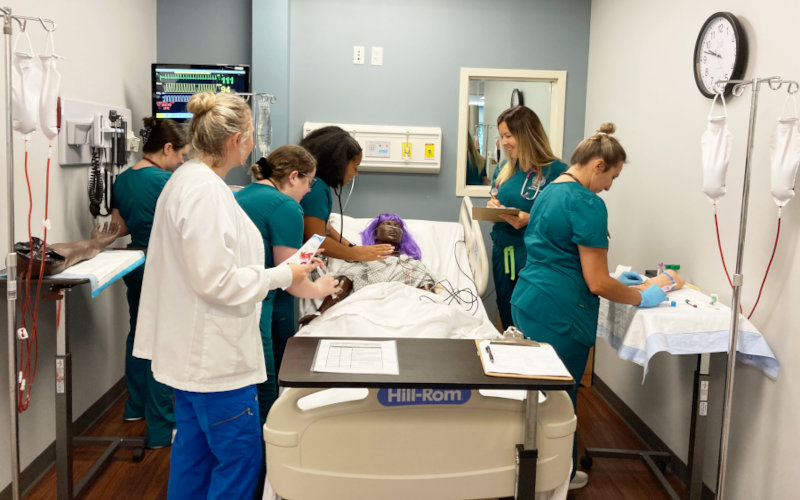 A nursing lab with students around a simulation patient.