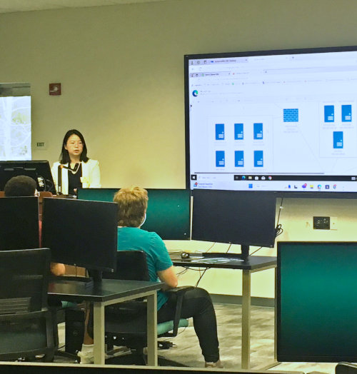 A teacher and pupils in a classroom learning about cyber security topics.