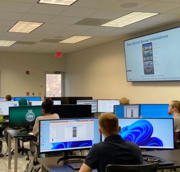 A classroom with students facing a computer monitor