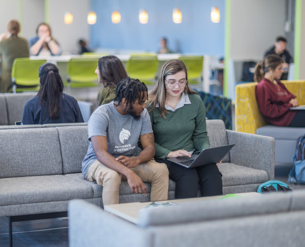 Students at study room seating with a laptop on their lap