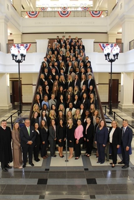 A group of law students in regalia posing on the College of Law staircase.
