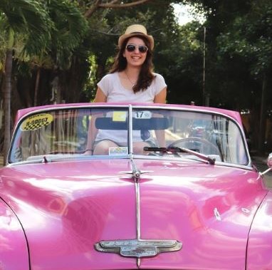Anna Tripp sitting on top of a pink convertible automobile.