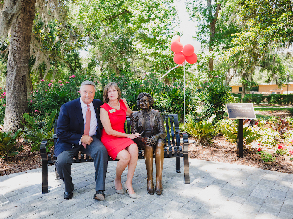 President Tim Cost '81 and Stephanie Cost sitting on the Francis Bartlett Kinne bench on JU's main campus