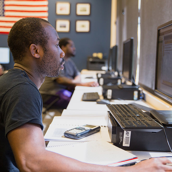 A young man works on a desktop computer.